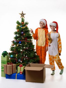 Two girls stand by the Christmas tree and hold festive tinsel in their hands.
