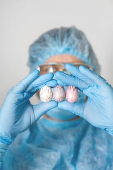 Hands in medical gloves holding modern painted easter eggs. Selective focus. Toned picture.