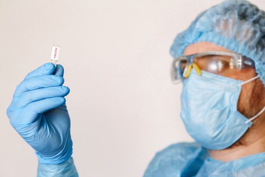 Close up of doctor hand holding vaccine. Medical equipment. A doctor wearing personal protective equipment including mask, goggle, and suit to protect COVID 19 coronavirus infection.