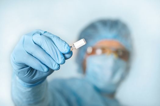 Close up of doctor hand holding vaccine. Medical equipment. A doctor wearing personal protective equipment including mask, goggle, and suit to protect COVID 19 coronavirus infection.