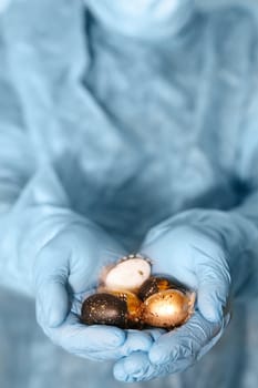 Hands in medical gloves holding modern painted easter eggs. Selective focus. Toned picture.