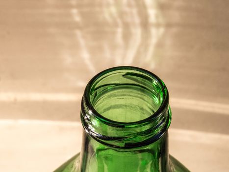 Bottleneck of green bottle in close up, with defocused light background