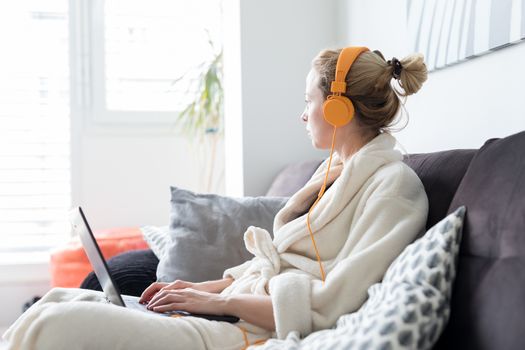 Stay at home and social distancing. Woman in her casual home bathrobe working remotly from her living room. Video chatting using social media with friend, family, business clients or partners.