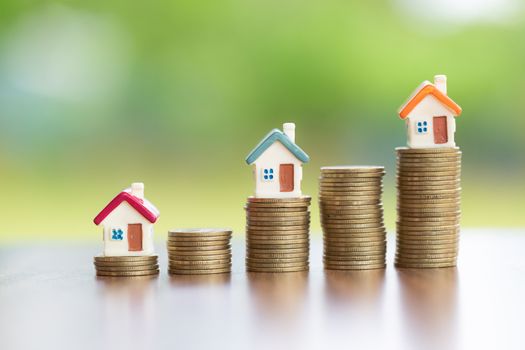  Saving money concept, coin stack growing business, save money for investment. coins to buy a home concept concept for property ladder. A small house on a pile of coins And have a financial chart.