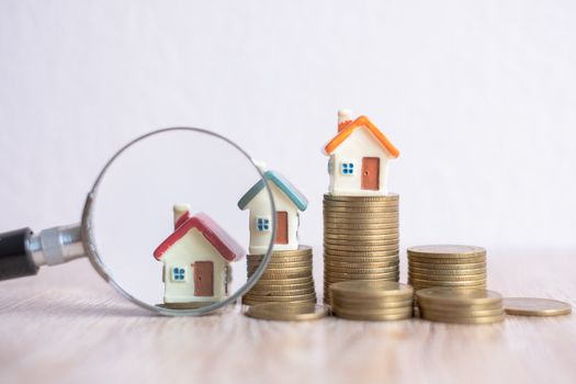 Miniature of house with magnifying glass and coin. house and money. toy house, magnifying glass and coins. concept of mortgage, construction, rental housing.