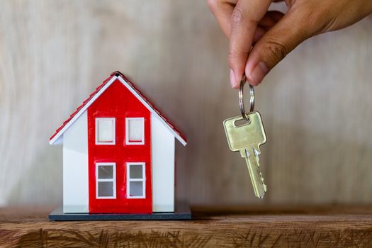 A real estate agent with a key. Red roof house. Offering home, property insurance, and housing safety concepts. Choosing a house in the future. Banking and home mortgages.