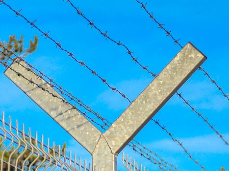 Selective focus. Security Fence In Prison. Lost freedom behind barbed wire. Old rusty barbed wire in the forest close up. Private property. Blue sky on background