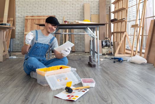 Asian carpenter inspect the list of items that must be done as scheduled, deliver the work with a happy face. Morning work atmosphere in the workshop room.