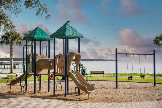 A colorful playground with swings and a sliding board in a park by the sea