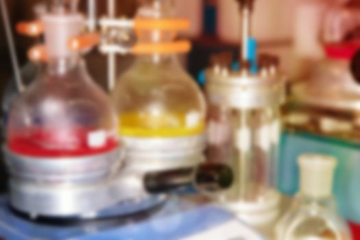 Blurred background of laboratory glass flasks with yellow and red liquid. The concept of scientific research and development.
