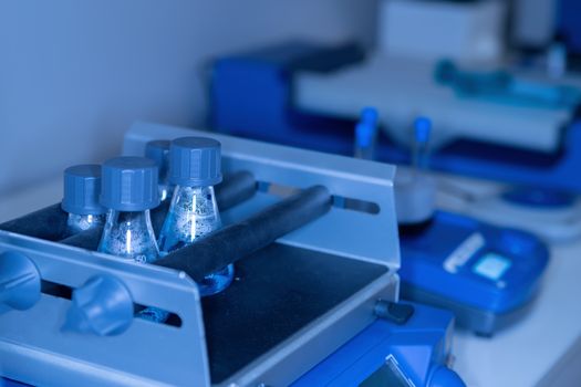 Close-up of a laboratory table with glass flasks and scientific instruments in blue tones. The concept of scientific research and development.