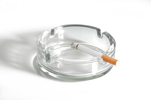 A cigarette lit in glass ashtray on white