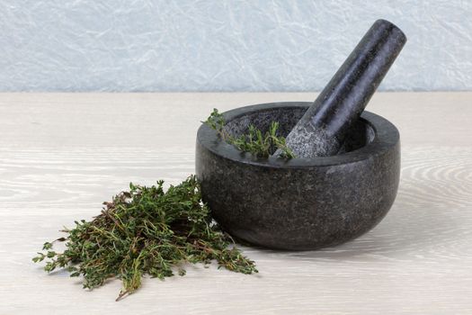 front view of fresh thyme on wooden kitchen surface and mortar and pestle