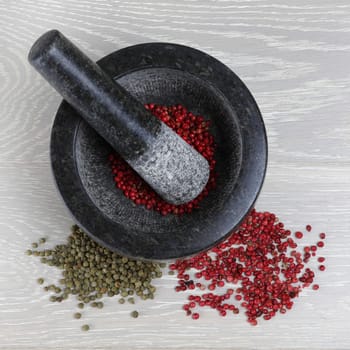 A top view of peppercorns with mortar and pestle on wood kitchen counter