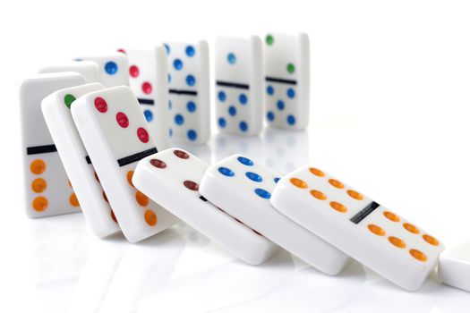 A line of falling colorful dominoes on a white surface