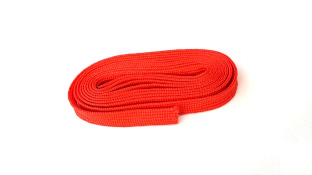 Red rope on white background. Fabric rope in red color folded in a coil.