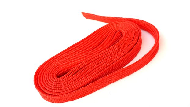 Red rope on white background. Fabric rope in red color folded in a coil.