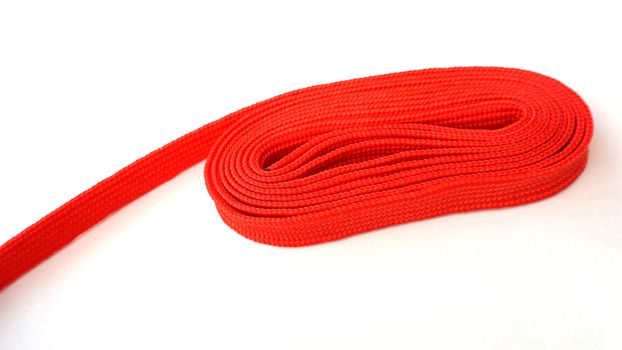 Red rope on white background. Fabric rope in red color folded in a coil.