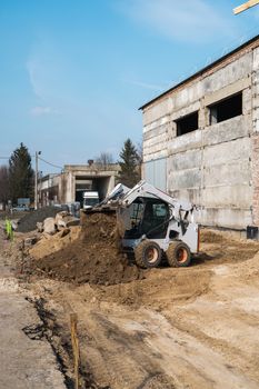 White skid steer loader at a construction site working with a soil. Industrial machinery. Industry