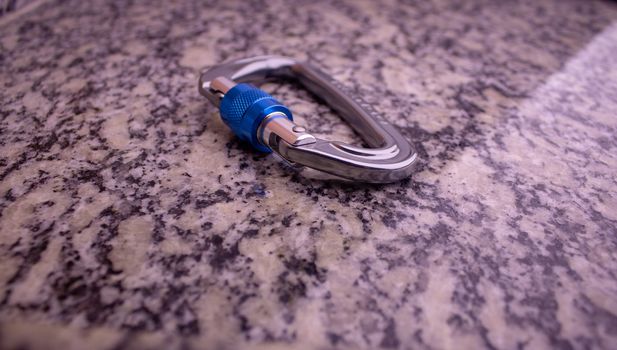 Screw gate carabiner used for rock climbing and mountain sports on a marble top