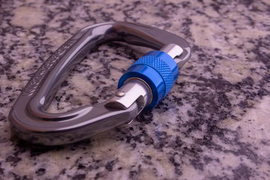 Screw gate carabiner used for rock climbing and mountain sports on a marble top