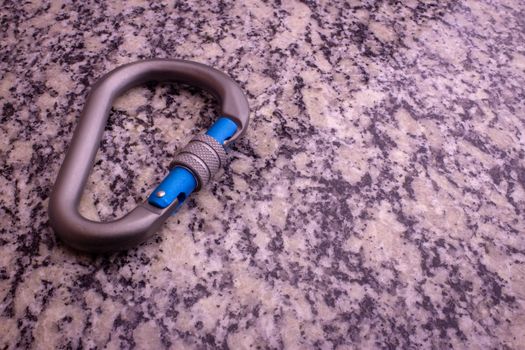 Screw gate carabiner used for rock climbing and mountain sports on a marble top