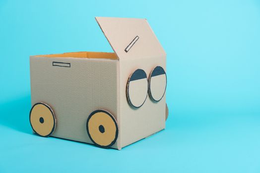 Car creative by a cardboard box imagination, summer holiday travel concept, studio shot on blue background with copy space for text