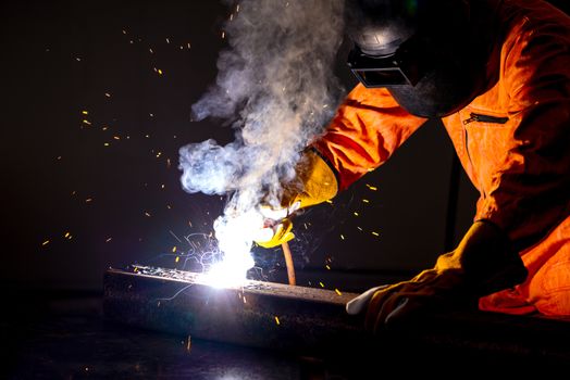 Metal industry workers are welding steel sheets for real estate projects received. Sparkler on dark background, close-up. Heavy work in factory.