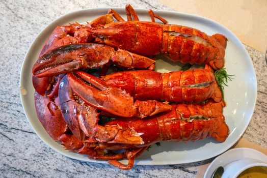 Three buttered Lobster prawns, neatly arranged on a white plate