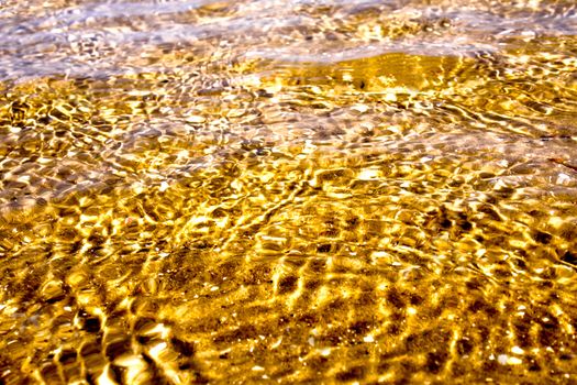 Reflection of sunlight on the moving sea water surface, sand beach and sea wave