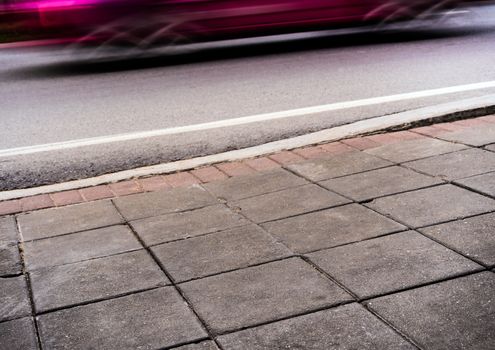 The road side pathway is paved with square blocks of concrete