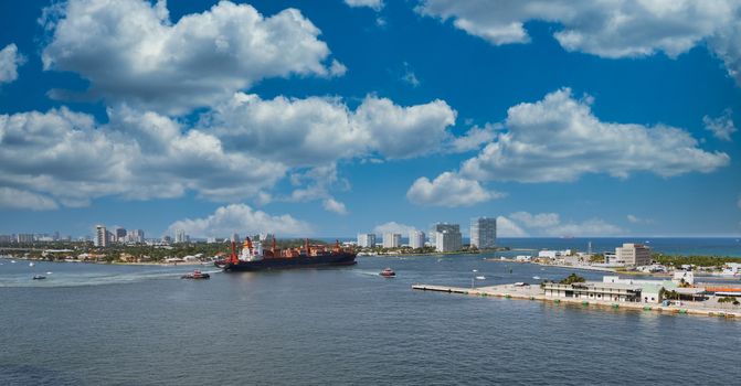 A loaded freighter leaving Fort Lauderdale harbor with tugboats