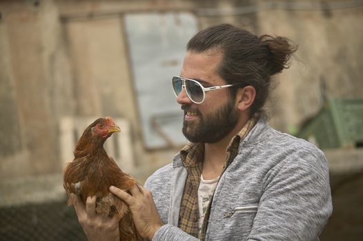 Young Farmer holds a live chicken in his hand