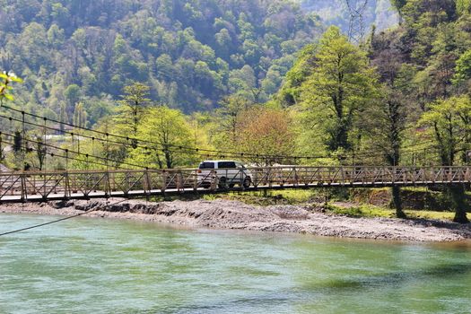 Photo of The car goes over the bridge over the river, which the villagers of Mirveti built themselves. Spring, Georgia