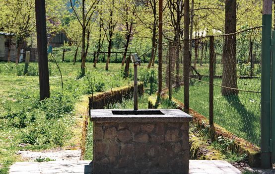 Photo of Tap with spring drinking water with a mug on the street, Mirveti village, Georgia