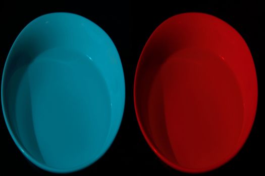 Two bowls with water of different colors, cyan, red, black background, complementary colors