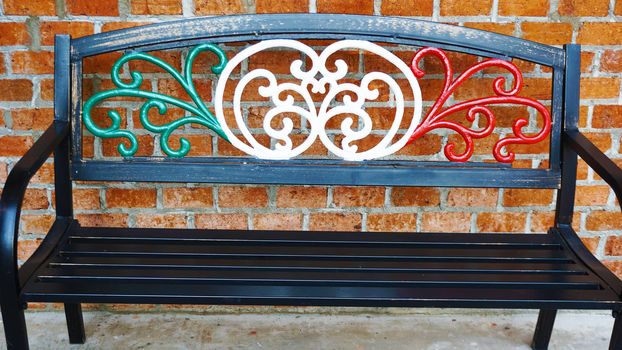 An iron bench chair draped in Italian flag colors outside of an Italian restaurant . Metal bench furniture for people waiting outside the restaurant.