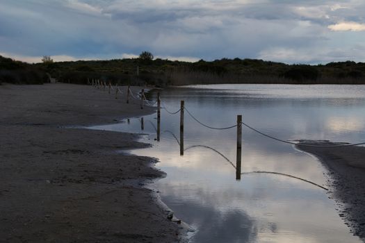 Dark clouds in sunset over the lake with a railing. Spring colors