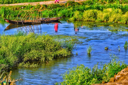 Small rural wetland surrounded by green bush with a old structure of boat