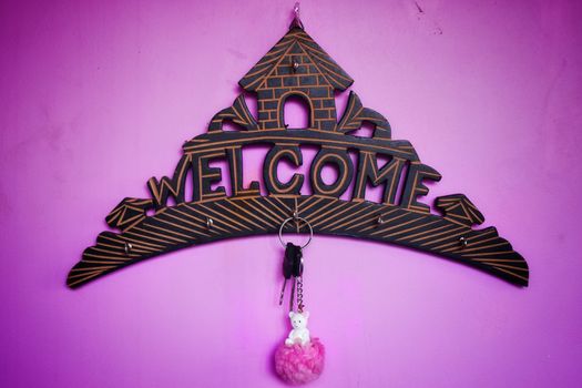 A beautifully designed wooden welcome board with hanging key with pink doll key ring