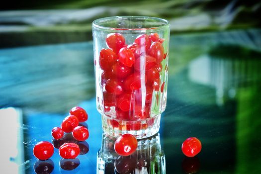 Lot of cherry fruits in a glass. Some cherry fruits are scattered on ground around the glass