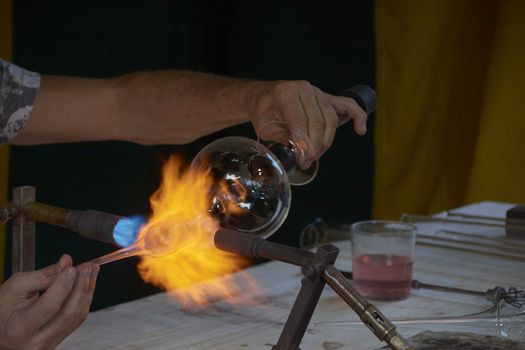 Skilful hands shaping hot and dangerous glass. ancient traditions
