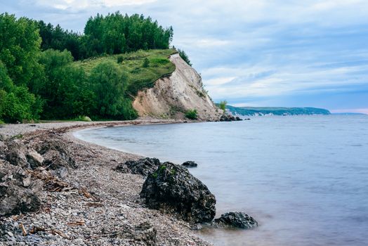 stone on the riverbank and cliff with birch woodland on background