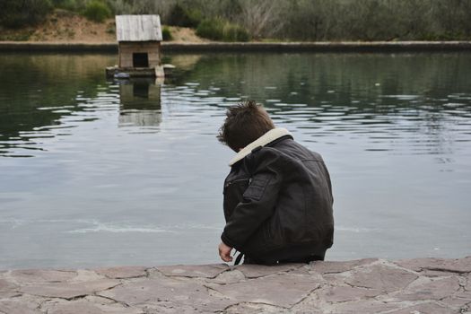 Dark boy watching the water raft with ducks, Colors of nature