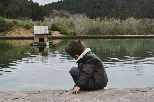 Dark boy watching the water raft with ducks, Colors of nature