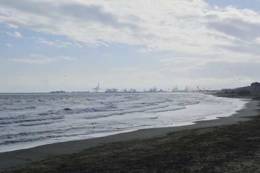 The port cranes seen from the beach. Machine colors