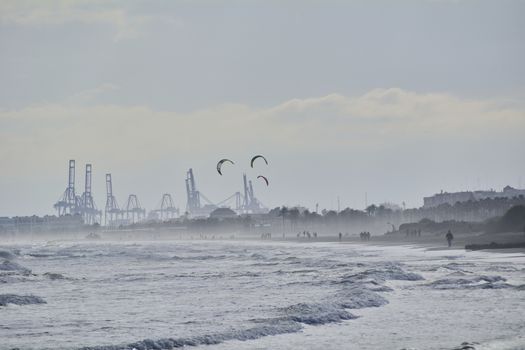 Harbor cranes with giant kites in front. Colors of nature