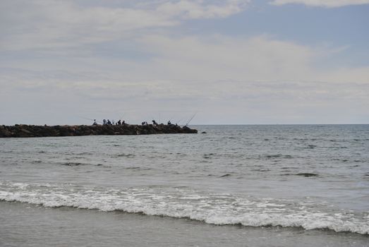 People fishing in the groynes on a bright day. Colors of nature