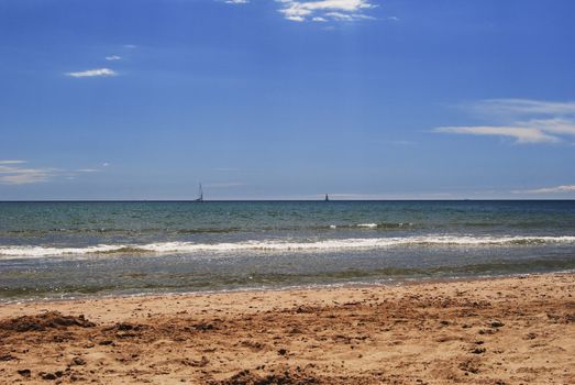 Sailboat sailing through the sea on a bright and calm day. Colors of nature