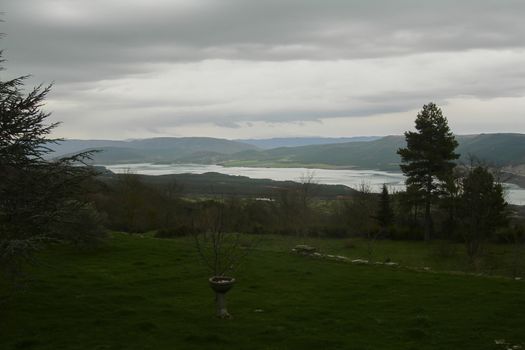 Fountain in a mountain landscape with a lake, Wet and green landscape with clouds in the sky